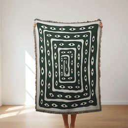 Mystic Gaze woven throw styled with deep green and ivory eye artwork